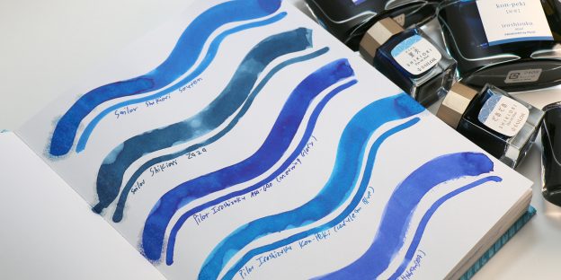 Side-by-side swatches of Sailor Shikiori vs Iroshizuku blue ink with ink bottles shown