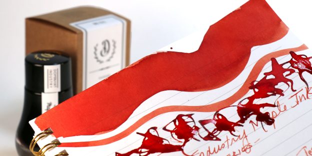 Dominant Industry Maple ink swatch and writing sample in warm red-orange terracotta tones.