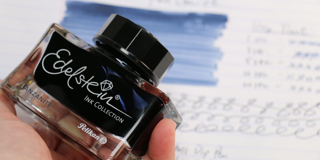 Pelikan Edelstein Tanzanite ink bottle held above ink test sheet