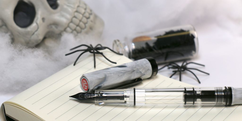 TWSBI ECO Carrera with Onyx Trim fountain pen uncapped on a notebook with Halloween props including skull, spiders, and cobwebs.