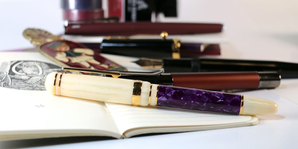 The Laban 325 in Wisteria, Lamy Studio in Orion, Magna Carta Mag 600, and Monteverde Ritma Espresso fountain pens with a vintage German brass page clip.