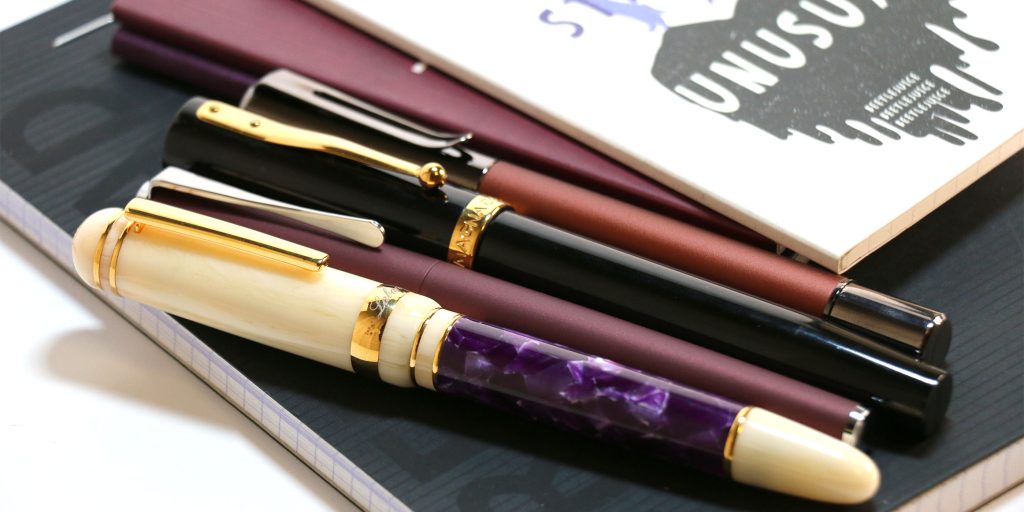 Four fountain pens capped: Laban 325 in Wisteria, Lamy Studio in Orion, Magna Carta Mag 600, and Monteverde Ritma Espresso.