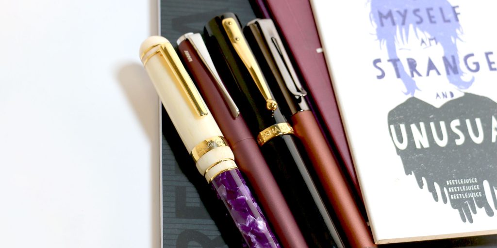 Four classic, vintage-inspired fountain pen designs: Laban 325 in Wisteria, Lamy Studio in Orion, Magna Carta Mag 600, and Monteverde Ritma Espresso.
