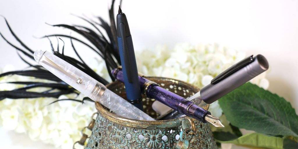3 luxury pens including the Sailor 1911 Grape Expectations uncapped showing the nib to represent the Moonlit Whispers Collection in Pen Chalet's 2025 Halloween Top Pens and Inks List