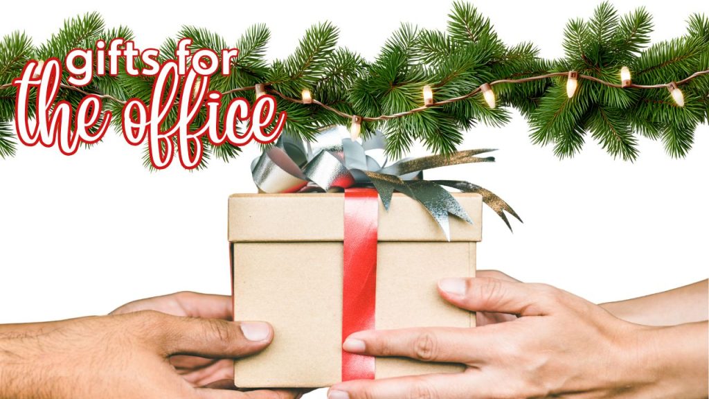 photo of gift with Christmas lights on evergreen garland behind with overlay indicating a title: Gifts for the office, co workers, boss, clients, and more in the 2025 Holiday Gift Guide for Pens and Inks