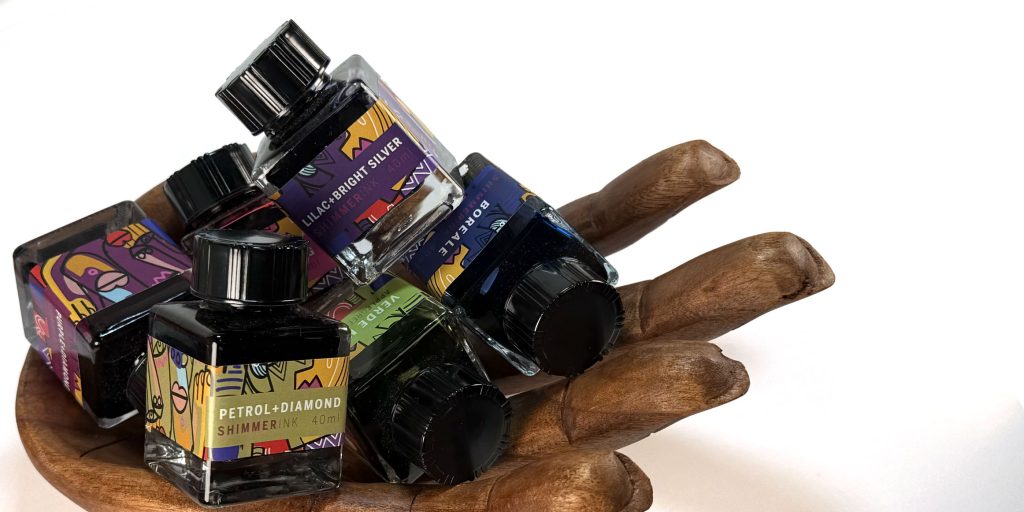 Photo of a container shaped like a wooden hand holding a variety of Leonardo Officina Italiana 40ml fountain pen inks in the 2025 Holiday Gift Guide for Pens and Inks' Stocking Stuffer section. 