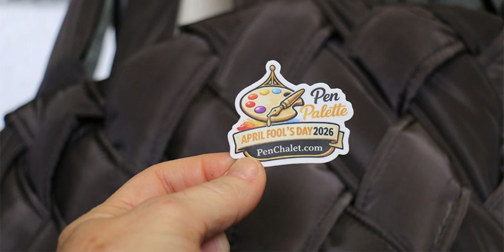 Hand holding Pen Palette April Fool’s Day 2026 sticker in front of pen case, revealing the Pen Chalet April Fool’s campaign