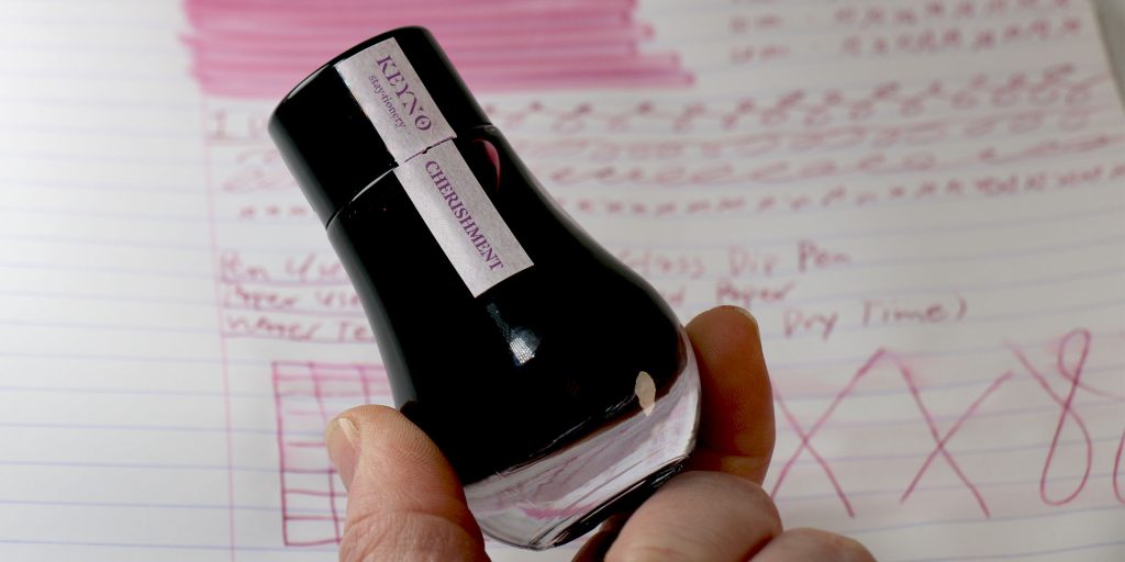Hand holding Keyno 014 Cherishment ink bottle over Pen Chalet test results