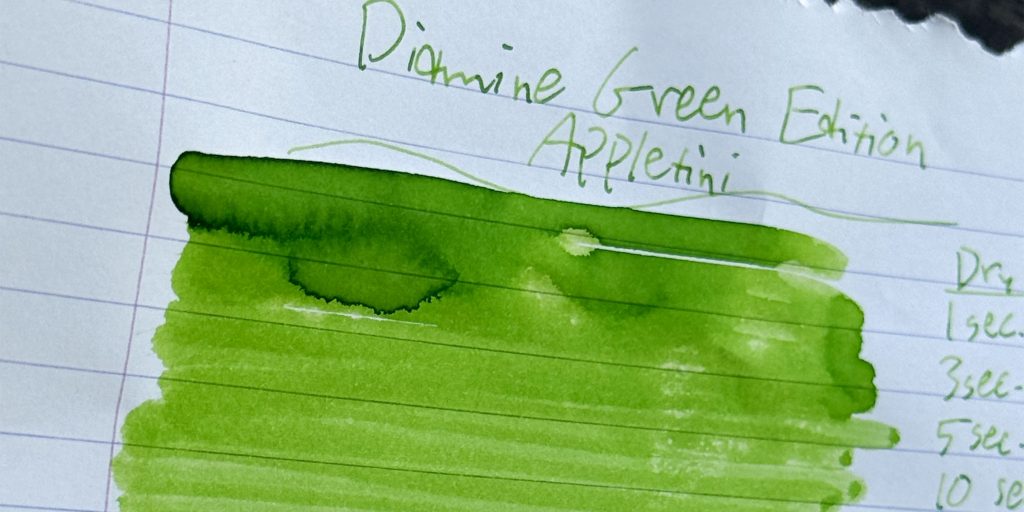 Close-up of Appletini ink swatches transitioning from deep grassy green to pale yellow-green on lined paper.