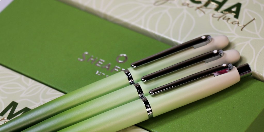 3 pens side by side on top of their pen boxes: fountain pen, rollerball, and ballpoint from the Sheaffer Matcha Collection.